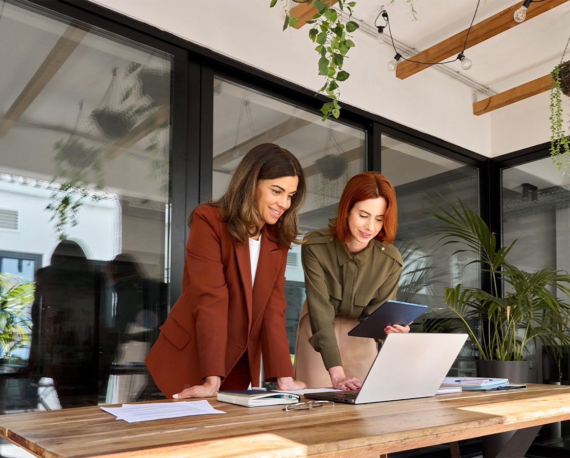 two woman looking at a computer on desk